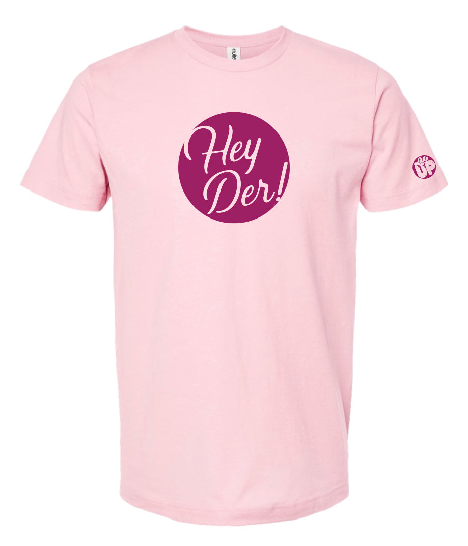 "Hey Der!" in script font, white on purple circle, on pink t-shirt on white background