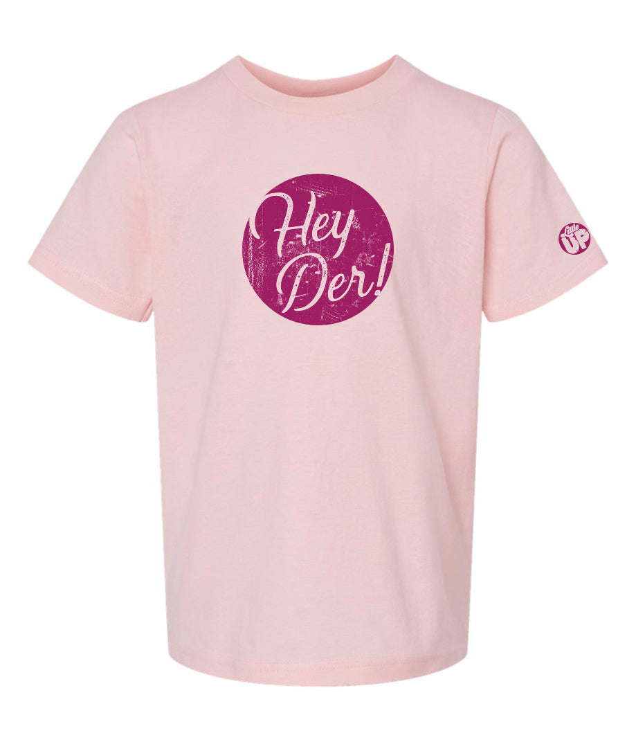 "Hey Der!" in script font, white on textured purple circle, on pink youth t-shirt on white background