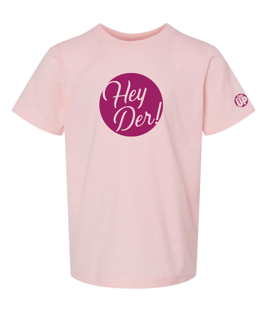 "Hey Der!" in script font, white on purple circle, on pink youth t-shirt on white background