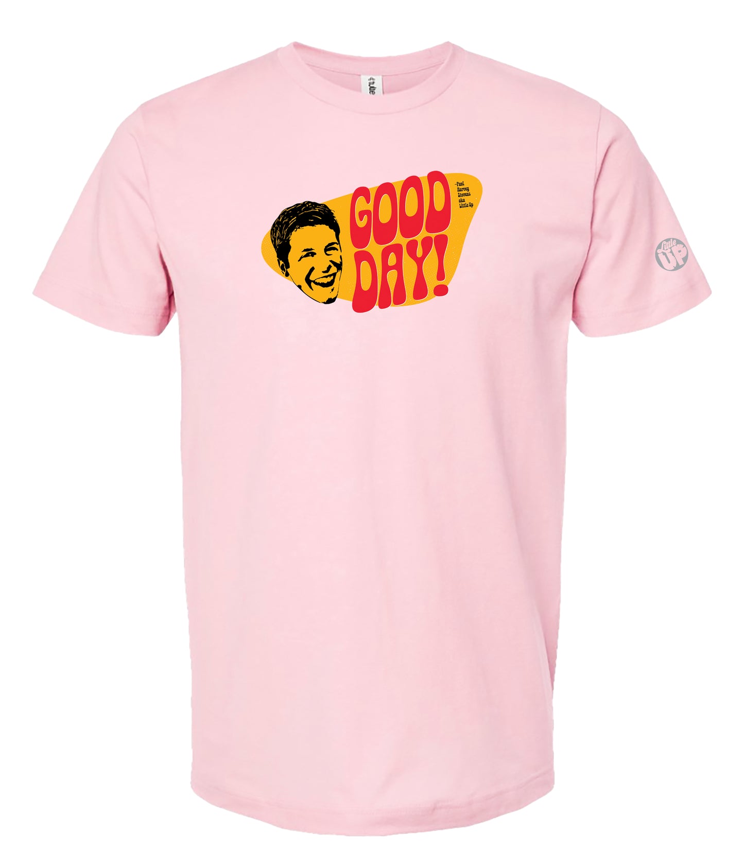 A light pink short-sleeve crewneck t-shirt featuring a retro graphic on the chest with the text 'GOOD DAY!' in red and yellow, alongside a stylized yellow face illustration.