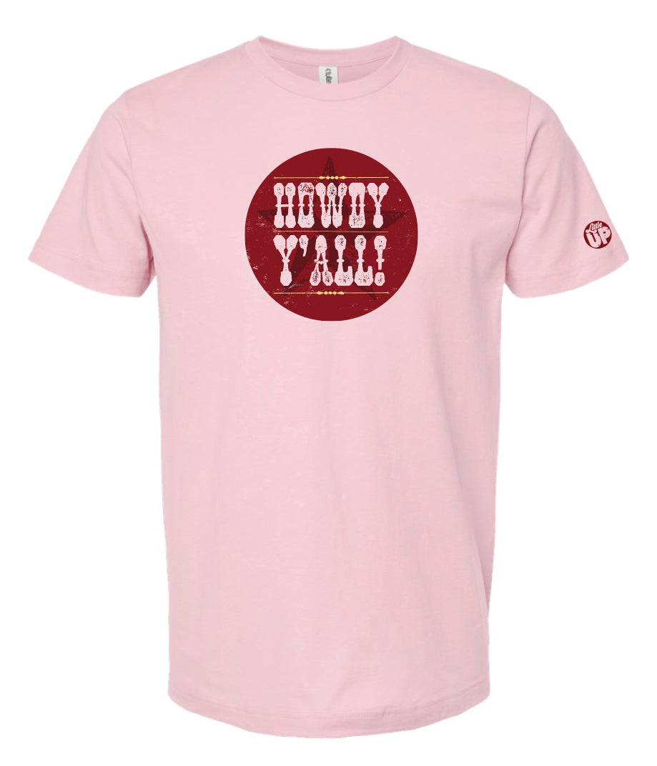 "HOWDY Y'ALL!" in textured western font on burgundy circle with subtle star overlay, on pink t-shirt