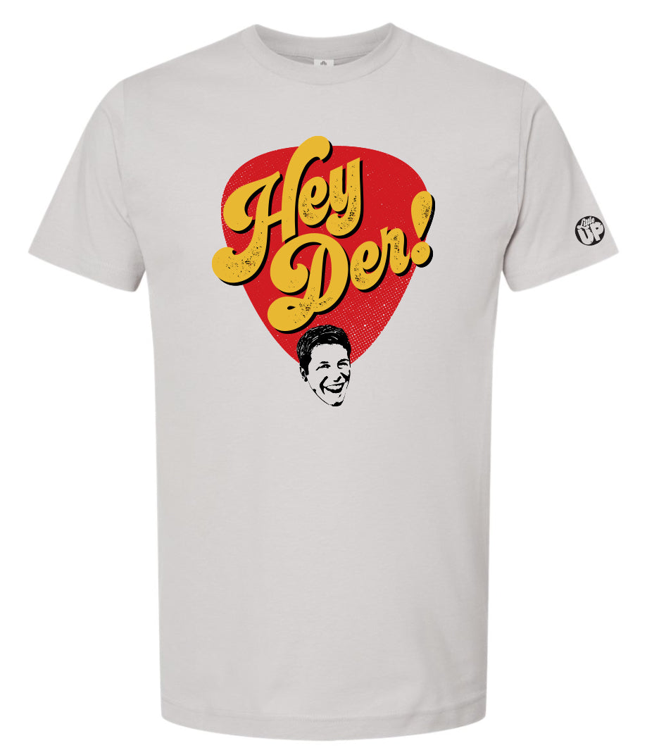 "HEY DER!" large in yellow 70s style script font in red teardrop shape with young man with big smile at the bottom on silver t-shirt
