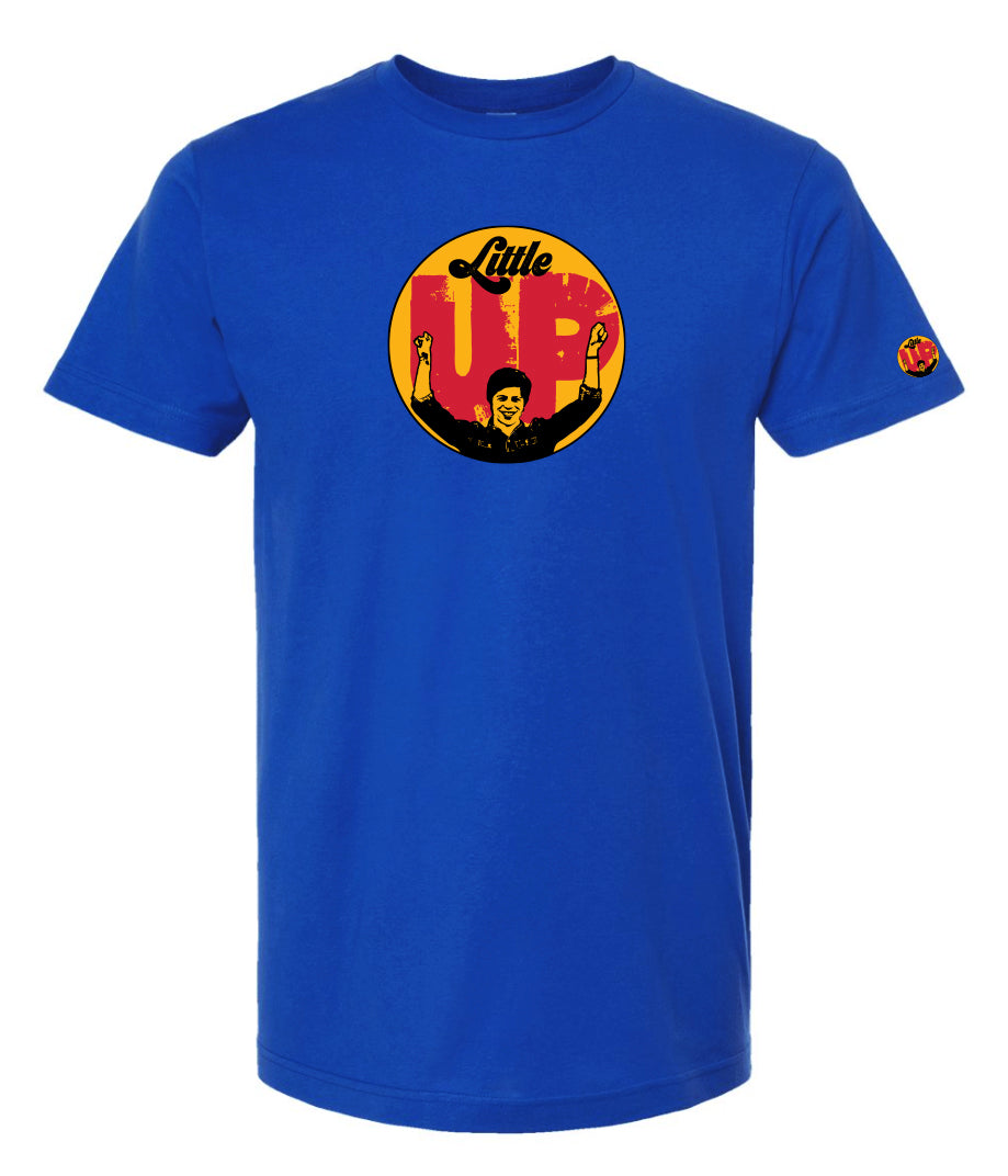 large circle with "Little" at the top in 70s script, "UP" large in red textured sans serif, illustration of young man smiling with arms raised illustration in black at the bottom, on royal blue t-shirt