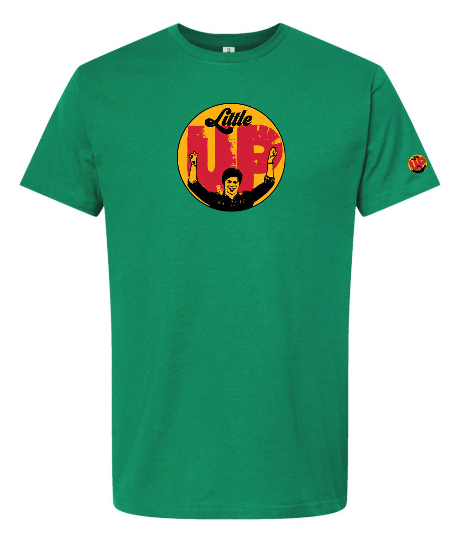 large circle with "Little" at the top in 70s script, "UP" large in red textured sans serif, illustration of young man smiling with arms raised illustration in black at the bottom, on green t-shirt