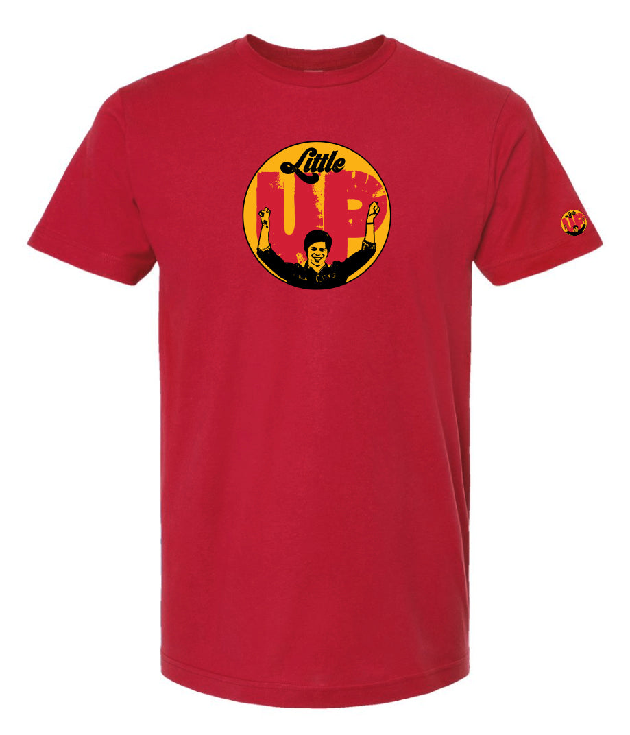 large circle with "Little" at the top in 70s script, "UP" large in red textured sans serif, illustration of young man smiling with arms raised illustration in black at the bottom, on red t-shirt