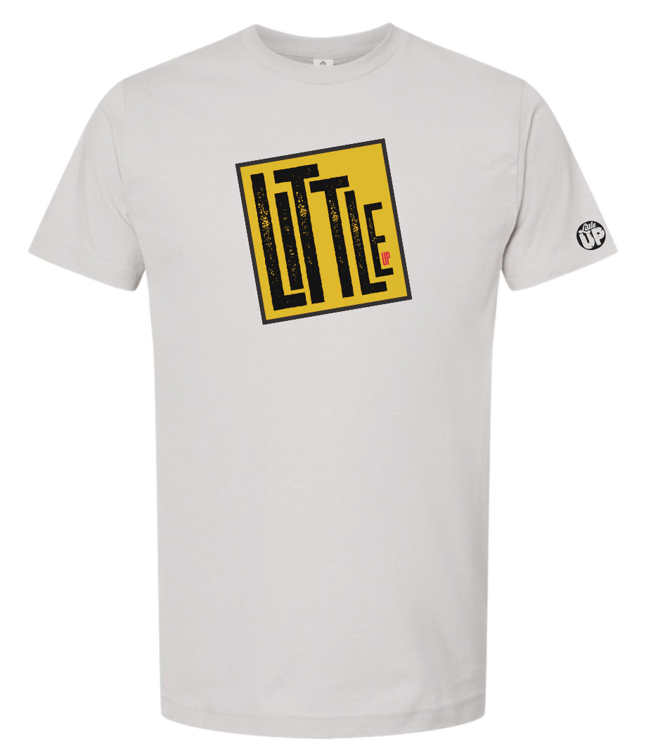 graphic in golden yellow tilted box with thick black border, "LITTLE" is very large, "UP" is very small in the lower right, printed on light gray tee on white background