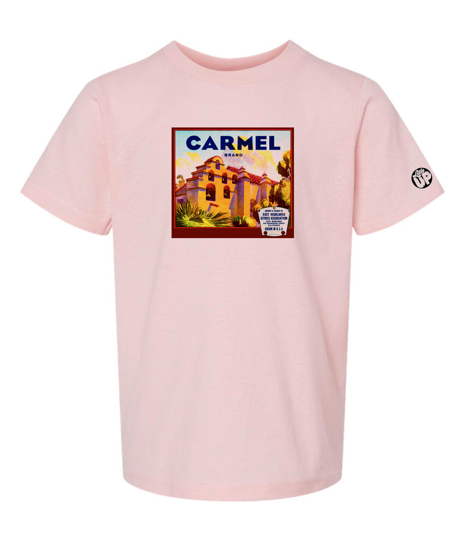 vintage "Carmel Brand" packaging graphic with old mission looking structure with terra cotta roof and stucco sides on pink youth tee on white background