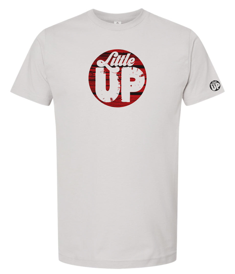 round logo with red wood background and "Little" in textured seventies script and "UP" big in sans serif textured font on light gray t-shirt on white background