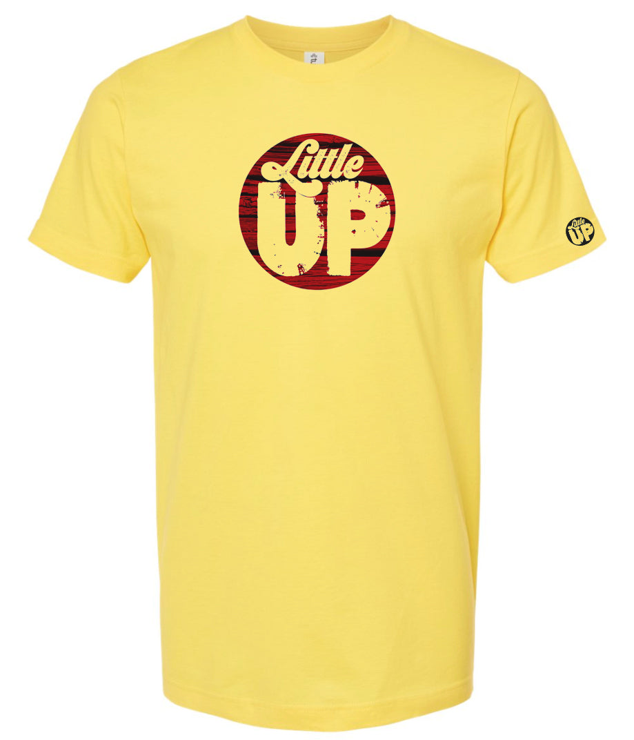 round logo with red wood background and "Little" in textured seventies script and "UP" big in sans serif textured font on yellow t-shirt on white background